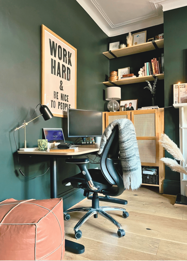 Image of a transformed living room into a multi-functional home office with dark green walls and a workspace. importance of lighting in a home office: desk lamp